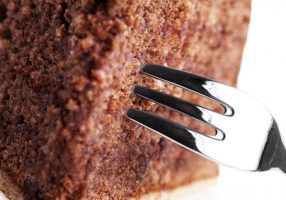macro closeup of a fork in a chocolate cake on white background